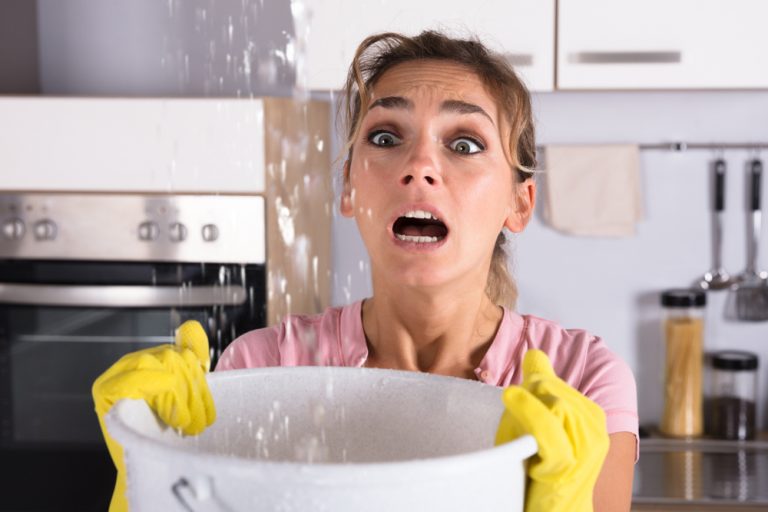 femme tenant un seau pour récupérer l'eau d'une fuite