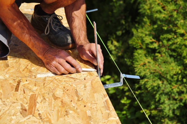 homme installant des fixations pour gouttière